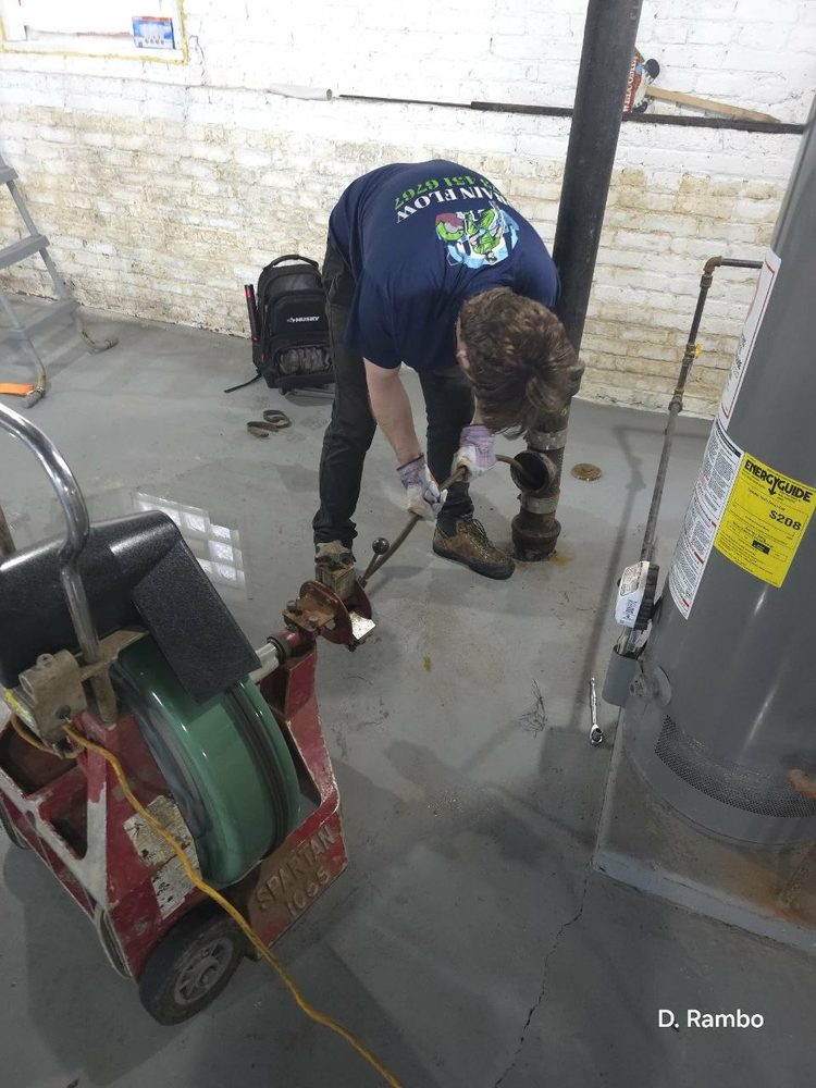 Technician clearing a main line with a power rodding machine